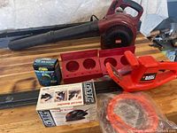 Photo showing Toro gas blower, Black & Decker hedge trimmer, boxed GMC palm sander, and new boxed heart rate monitor.