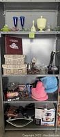 Shelf with assorted glassware, costume jewelry, baskets and boxed appliances