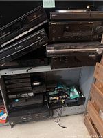 Shelf with various home audio equipment including cassette player, CD player, DVD player, tuners, receivers, and turntable.