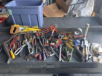 Overview of miscellaneous tool lot showing saw, wrenches, pliers, screwdrivers, clamps, and paint supplies.
