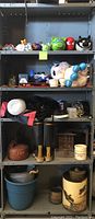 Full view of metal shelving unit with piggy banks, toys, games, water containers, boots and miscellaneous items.