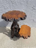 Full side angle showing the upper larger round live-edge top and the smaller lower live-edge surface, highlighting the natural texture of the cypress wood and complex sculpted base.