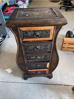 Front view showing the curved dresser with five drawers and floral carvings, bottom drawer damaged.