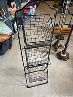 Front view of black metal wire basket shelving unit with three wire baskets vertically stacked.