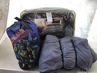 Lot setup showing Teenage Mutant Ninja Turtles blue sleeping bag, dark grey sleeping bag, and packaged striped bedding set.