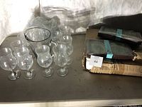 Photo of glass pitcher and eight matching goblet-style glass cups. Some items stacked next to the lot.