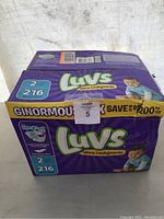 Front view of large purple box of Luvs size 2 diapers with branding and baby image