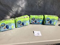 Four packs of Little Swimmers baby swimming diapers arranged on a table showing front packaging and branding.