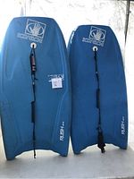 Two blue Body Glove water buggy boards laid side by side, showing their top surfaces including branded logos and leashes attached.