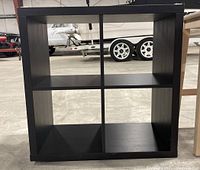 Front view of black cube storage unit showing four compartments and its overall condition