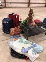 Wider view of lot showing suitcases, decorations, shower curtain, table and some packed items