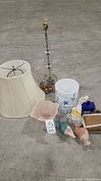 Full lot showing glass lamp with shade, ceramic containers, and several figurines including glass mermaids and small house containers.