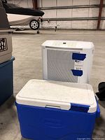 Frigidaire Gallery dehumidifier and blue and white Coleman cooler in a warehouse setting