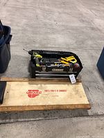 Top view of toolbox filled with miscellaneous tools and the Carquest wooden roller beside it