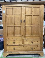 Front view of vintage solid wood cabinet showing two paneled doors and three drawers beneath.