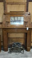 Front view of vintage wooden mantle with attached mirror and faux fireplace insert, showing overall condition and design