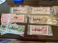 Six sleeves of Canadian Tire Money displayed on a table, each sleeve marked with a dollar amount and containing multiple bills of various denominations.