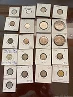 Photo showing assortment of coins in cardboard holders with written years and countries, mainly Canadian and Newfoundland coins along with Chile and Finland coins.