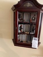 Wall-mounted wooden display cabinet showing three shelves of miniature tools