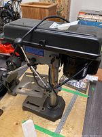 Front and side view of King Canada bench drill press on table surface showing overall assembly and control handle.