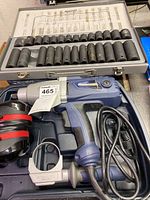 Electric impact wrench and socket set laid out in case with power cord and auxiliary handle visible.