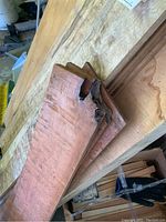 Three figured maple boards stacked on a plywood surface
