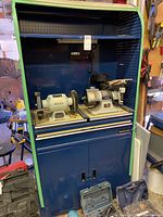 Front view of blue Mastercraft metal tool cabinet with pegboard back and two bench grinders on sliding shelf