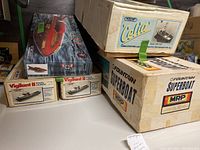 Five boxed model boat kits on surface: speedboat, trawler, superboat, and police launches