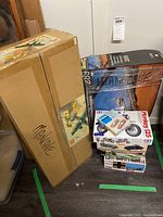 Lot of plastic model kits stacked, including airplane, motorcycle and excavator models in their original packaging boxes.