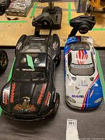 Overhead view of three RC vehicles and two transmitters on workbench
