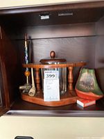 Full view of wooden rack holding glass jar and multiple smoking pipes with accessories.