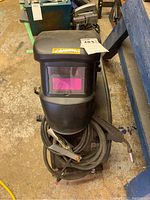 Front view of black Samona welding helmet on Mastercraft welder unit with coiled cables