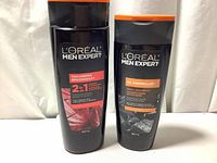 Front view of two L'Oreal Men Expert shampoo bottles, showing Thickening 2-in-1 and Oil Controller Daily Shampoo bottles with their labels clear.