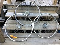 Three bicycle wheels arranged on wooden steps. Two larger wheels are 25 inch, and one smaller wheel is 21 inch. One wheel fitted with Bianchi tire.