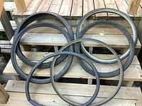 Six used bicycle tires of various brands and sizes laid out on wooden steps, showing tread variety and condition.