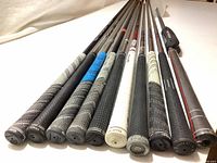 Photo showing ends of golf shafts with various grips including Golf Pride and Lamkin, highlighting grip condition and style.