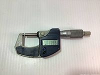 Mitutoyo Digimatic micrometer showing digital reading 0.1755 on LCD display, full frame showing blue metal body and silver knurled thimble