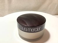 Laura Mercier loose setting powder container with lid showing front branding.