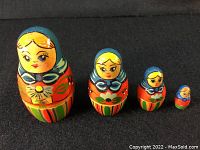 Photo showing four vintage Russian/Ukrainian nesting dolls arranged in a row by size from largest to smallest on a black surface.