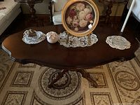 Top view of oval mahogany coffee table on patterned rug with decorative items