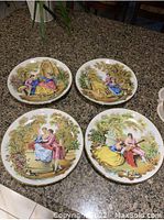 Four Gloria Fine Porcelain Bayreuth decorative plates arranged on a table showing the painted romantic couple garden scenes.