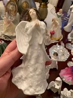 Front view of white porcelain Royal Doulton angel figurine with detailed wings and praying hands, showing floral textured gown and serene face.
