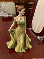 Photo of the green dress female figurine on a wooden table.