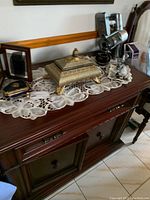 Sideboard buffet made of cherry wood with two cabinets and a drawer, shown with various decorative items on top.