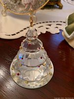 Close-up of Swarovski crystal Christmas tree figurine showing clear faceted crystal with red and gold accents and star topper.