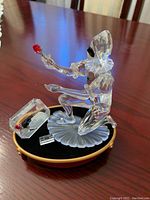 Facet-cut clear crystal Harlequin figure kneeling on frosted petal-shape base holding red rose