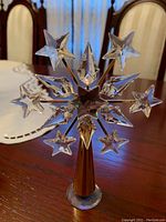 Clear view of the Swarovski crystal star tree topper with multiple crystal points and gold-toned cone base on a wooden table.