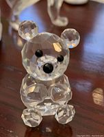 Close-up photo of a vintage Swarovski crystal teddy bear figurine, showing its clear faceted crystal body and black eyes and nose.