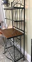 Front angled view of the baker's rack highlighting top metal shelves, middle wood shelf, and metal frame.