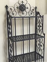 Front view of 4-shelf metal baker's rack with decorative scrollwork and lattice shelves.